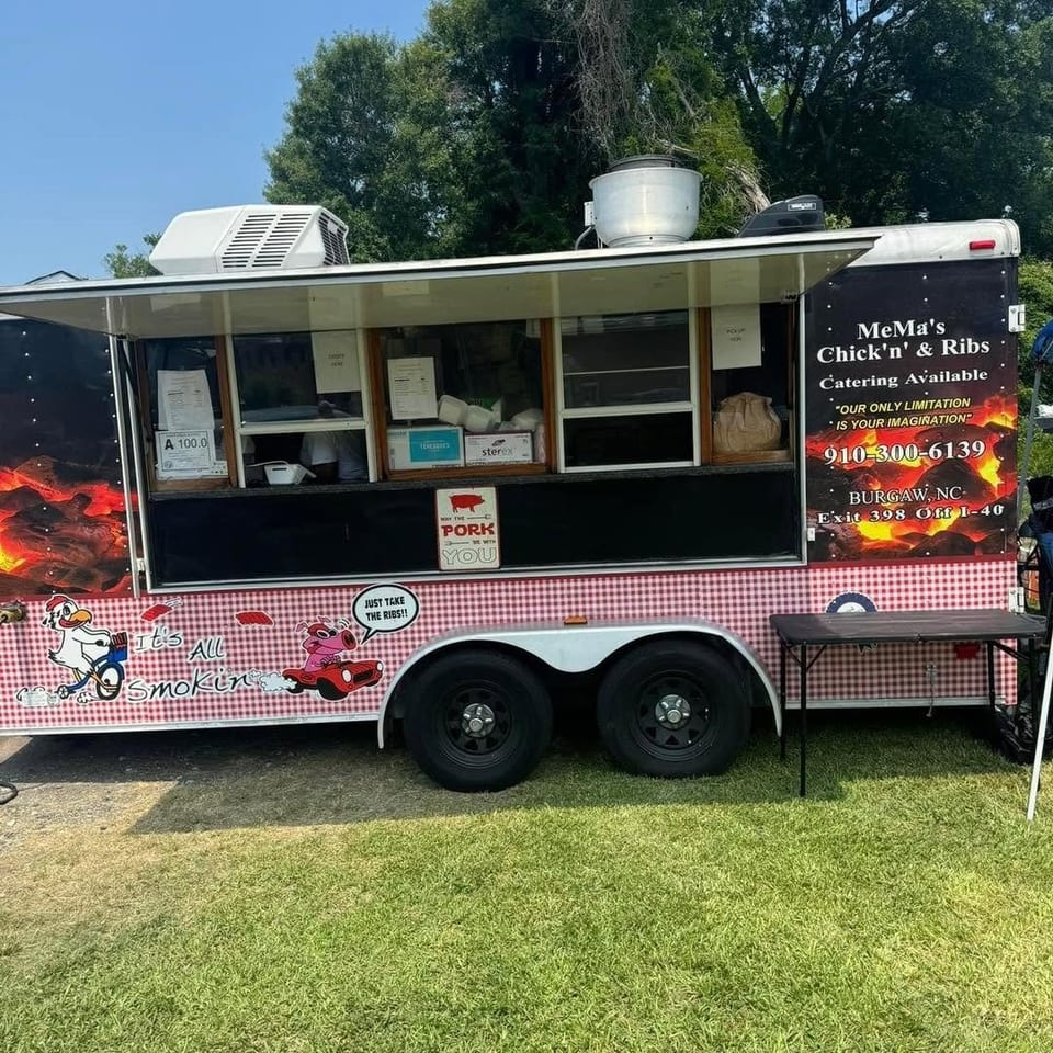 MeMa’s Chick’n & Ribs catering food truck parked on grass, decorated with barbecue graphics, picnic tablecloth trim, and menu windows.